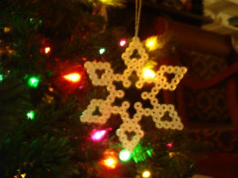 A Perler bead ornament on a lit Christmas tree.