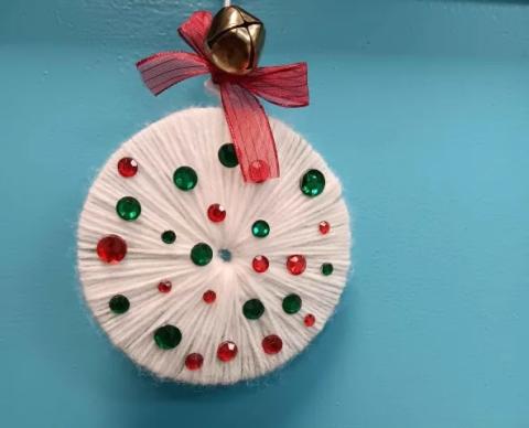 A round yarn ornament with red and green decorations.