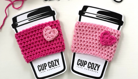 Two crocheted cup cozies with hearts in alternating pinks