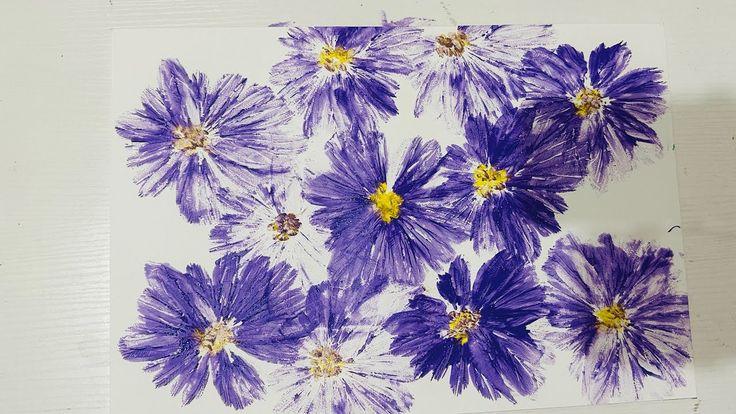 Purple flowers with yellow centers, painted using an inflated plastic bag. 