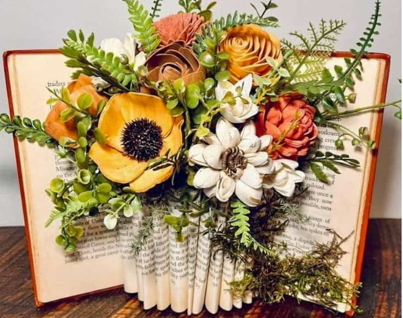 A book folded into a vase with sprigs of seasonal flowers