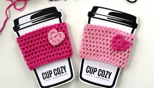 Two crocheted cup cozies with hearts in alternating pinks